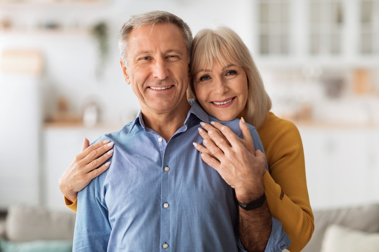 Senior Wife Embracing Husband Posing Together Standing In Kitchen